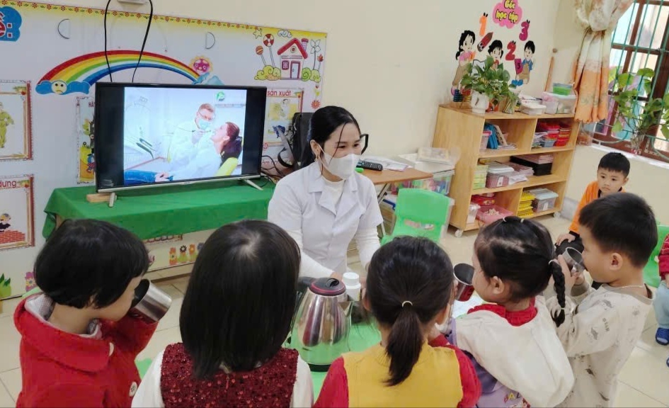 Hình ảnh cán bộ y tế cho trẻ uống thuốc tẩy giun tại trường mầm non